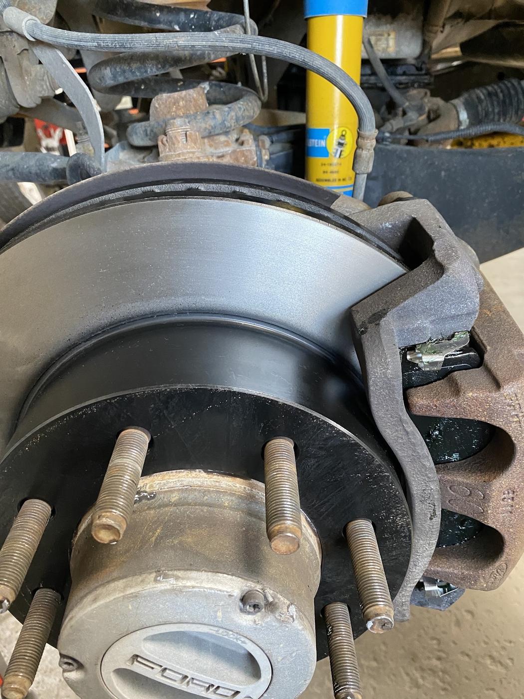 Close-up of a brake rotor and caliper on a truck hub, with a shock behind it