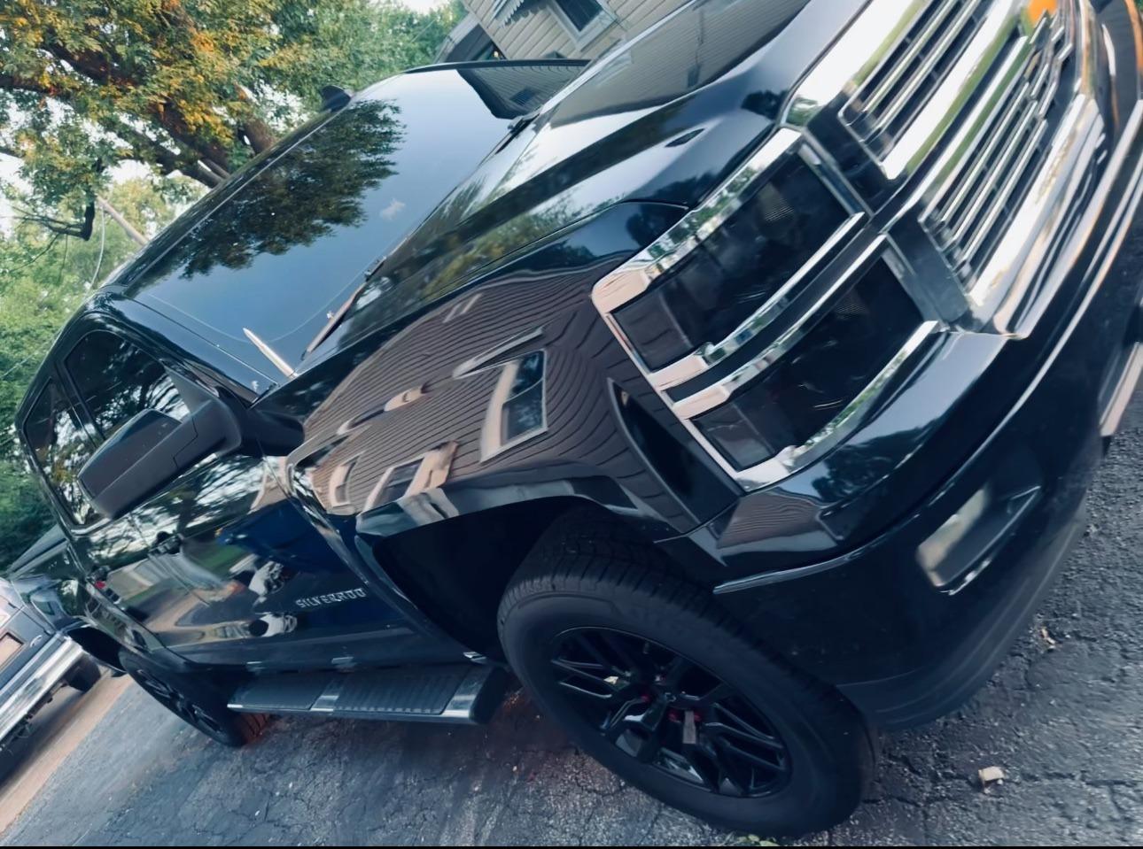 A lifted black pickup, front three-quarter view