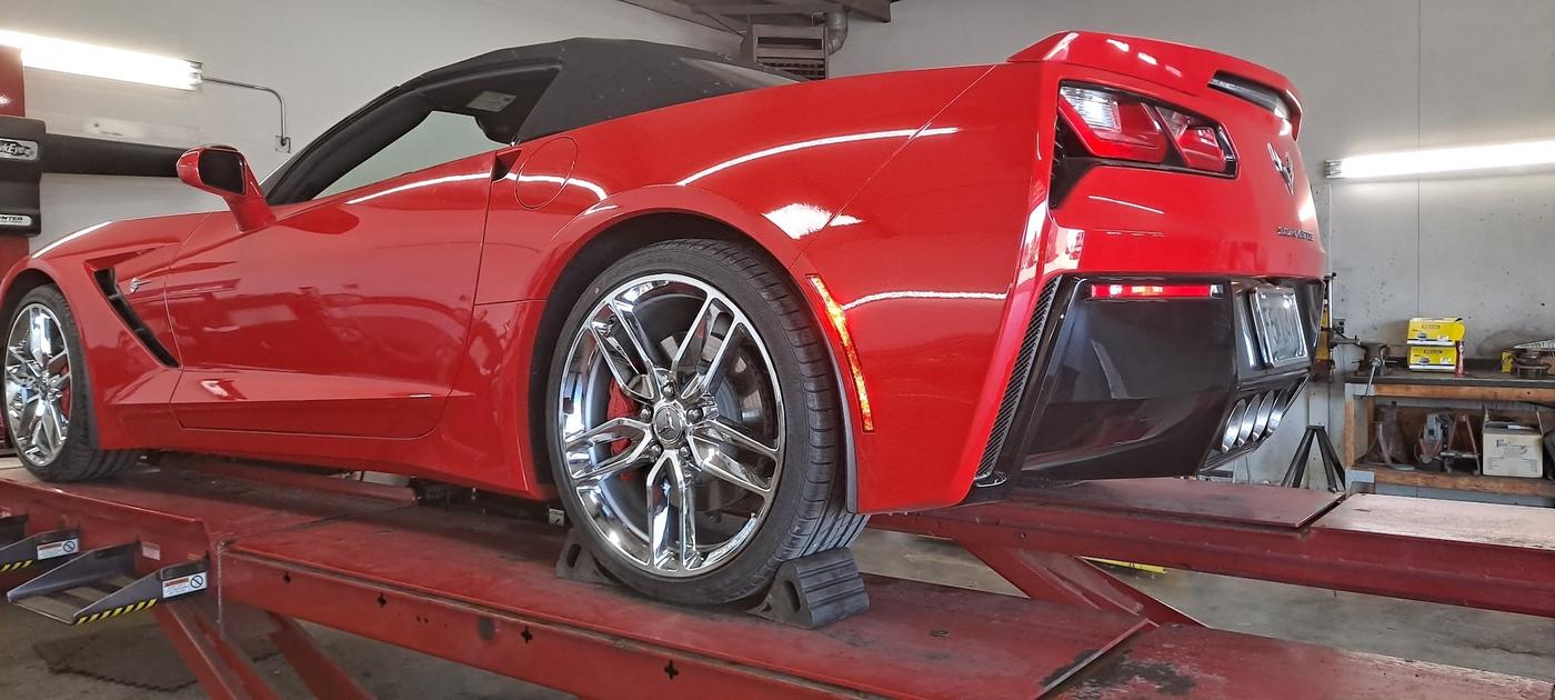 A red Corvette on the red alignment rack