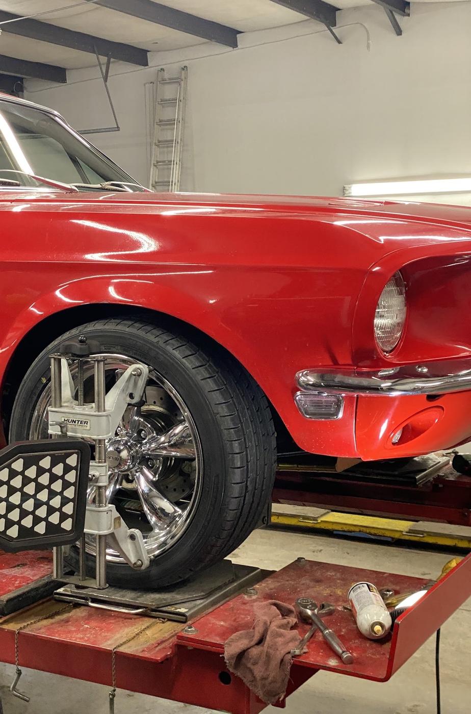 A red Mustang wheel on the rack with an alignment target clamped to it