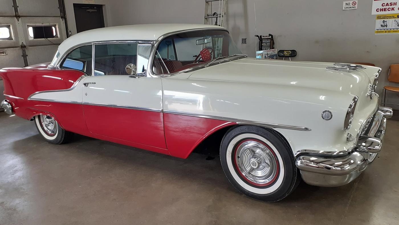 A red and white classic sedan inside the shop