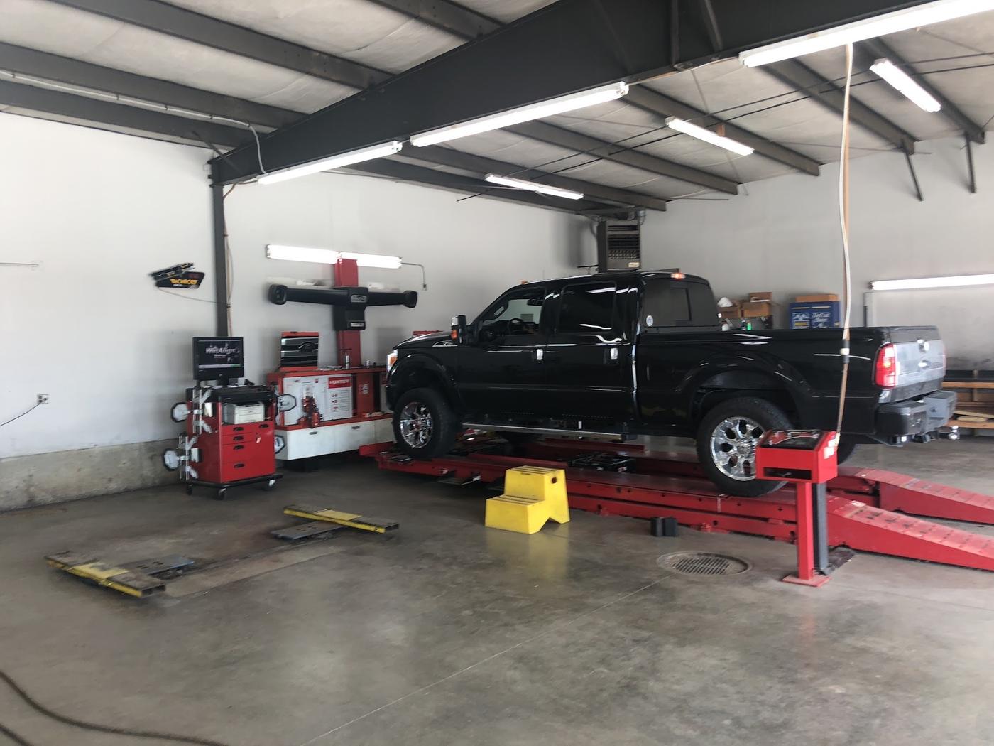 A black pickup up on the red alignment rack beside the alignment console